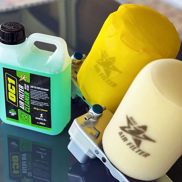 Das Präparat OC1 Air Filter Cleaner neben Schaumstoff-Luftfiltern eines Motorrads