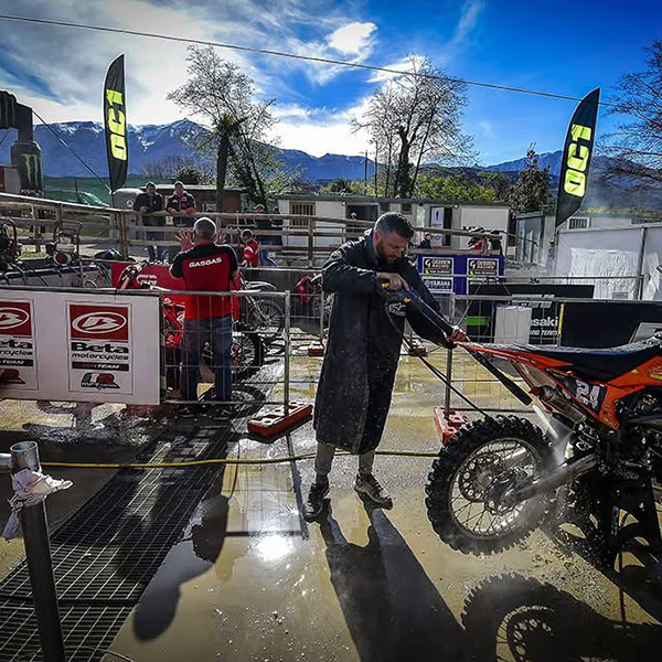 Enduro-Motorrad wird im Fahrerlager mit dem Hochdruckreiniger gewaschen